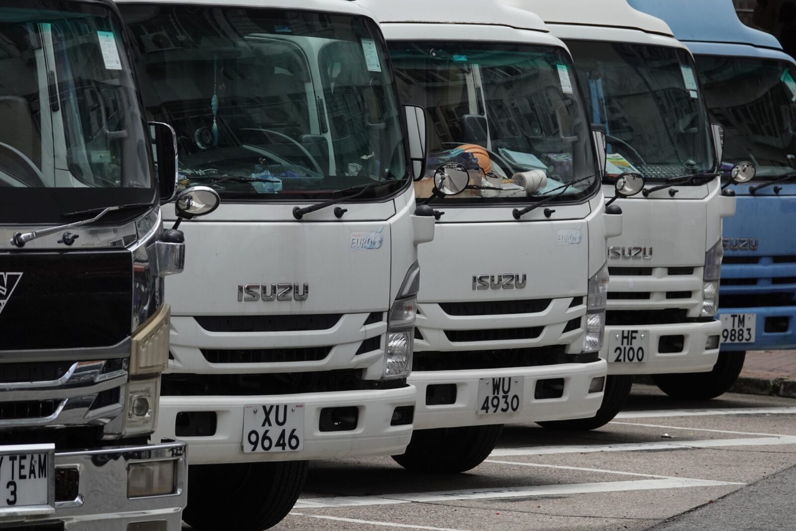 Parked Isuzu trucks lined up in the city, ready for delivery. Ideal for transport and logistics themes.